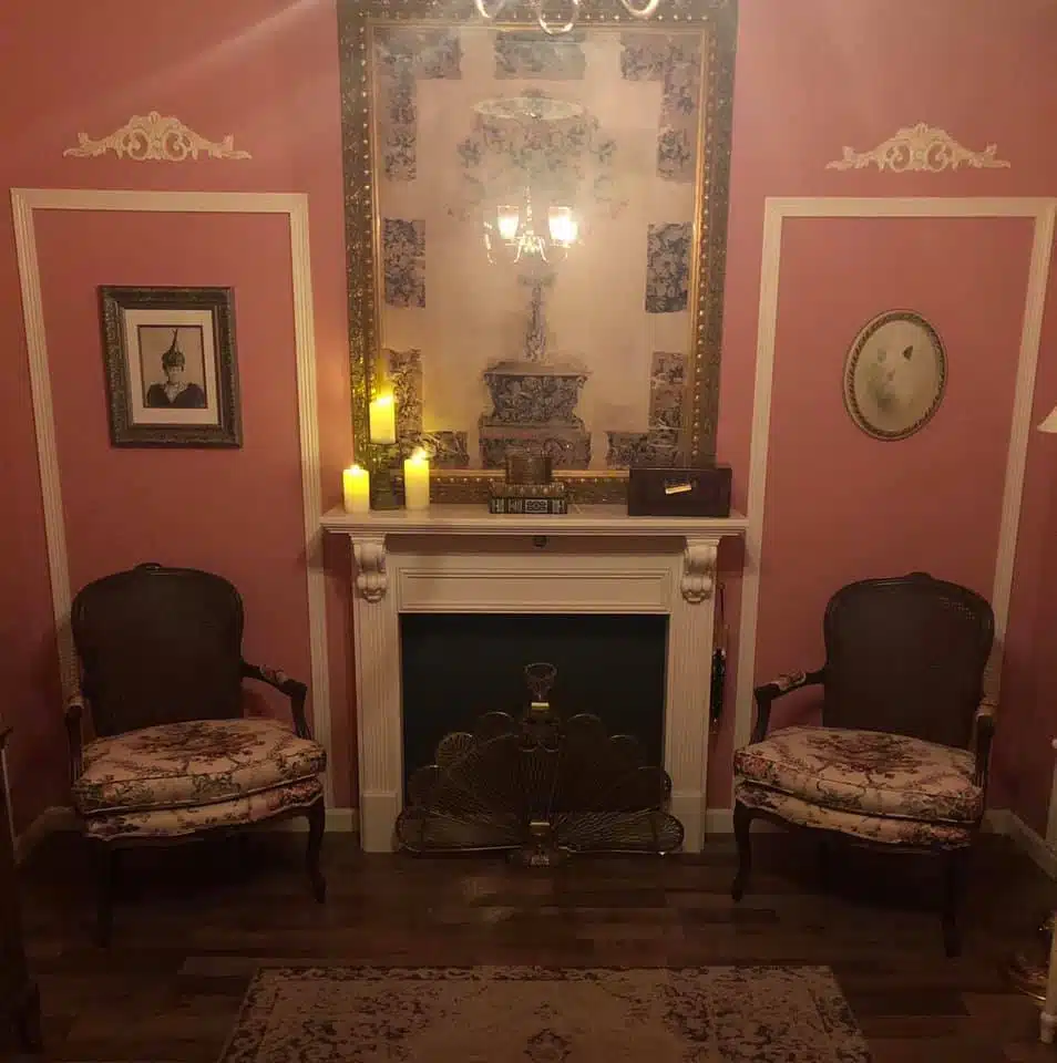 An Image of the Haunted escape room Frederick MD. A fireplace with old victorian furniture in an eerie room.