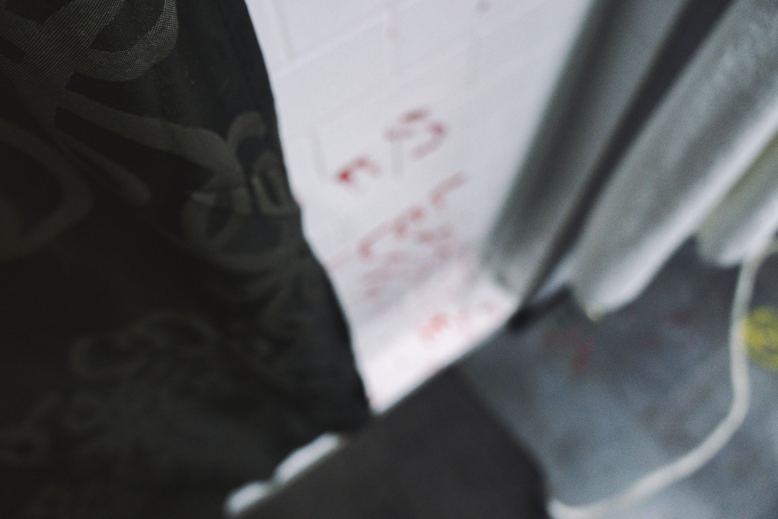 An image of the Crime Scene escape room at Escape This Frederick. The image is blurred with a shower and some red marks in the background.