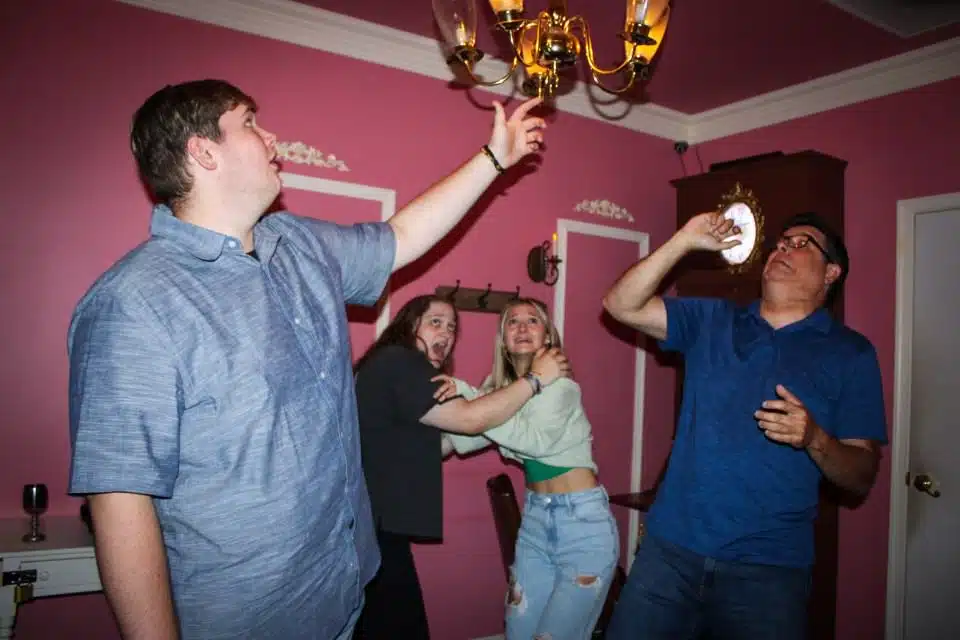 An image of the Haunted escape room at Escape This Frederick. Four escape room players seem terrified looking into the ceiling.