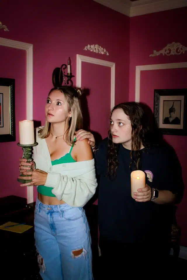 An Image of the Haunted escape room Frederick MD. Two girls look scared holding candles as if frightened by something.